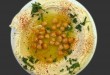 plate of hummus with chickpeas, black background
