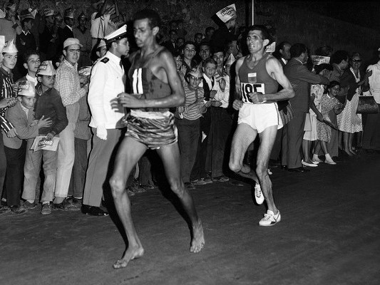 Why does Abebe Bikila run without shoes?Abebe Bikila - Wikipedia 1960 Rome Olympics In Rome, Abebe purchased new running shoes, but they did not fit well and gave him blisters. He consequently decided to run barefoot instead.