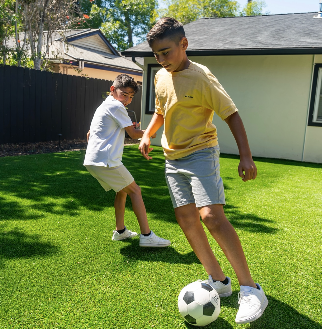 boys playing soccer in the back yard on fake, plastic grass. Artificial turf supply, Maryland