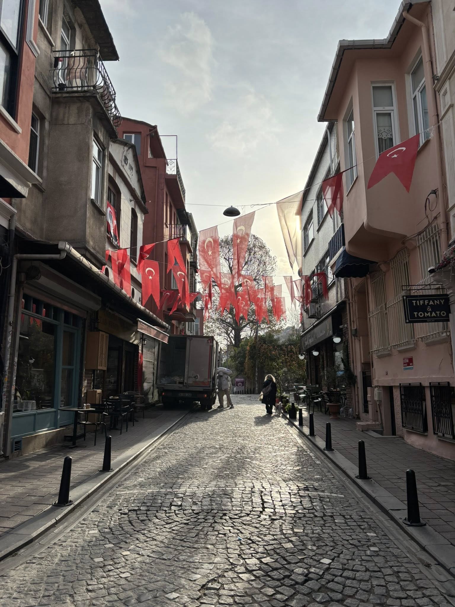 Flags and laundry strung above a narrow Balat street in Istanbul