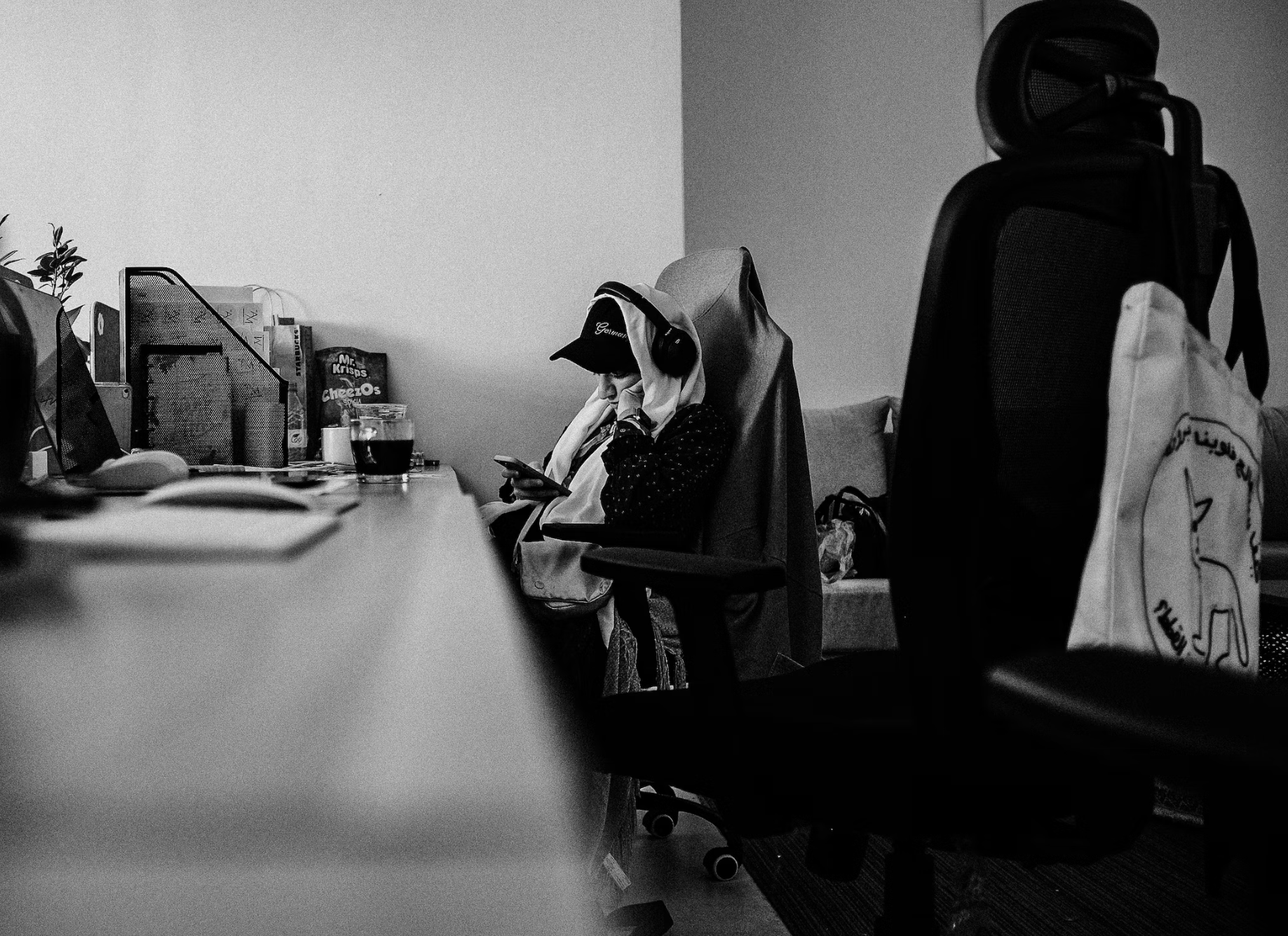 bored office worker in Saudi Arabia, looking at her phone