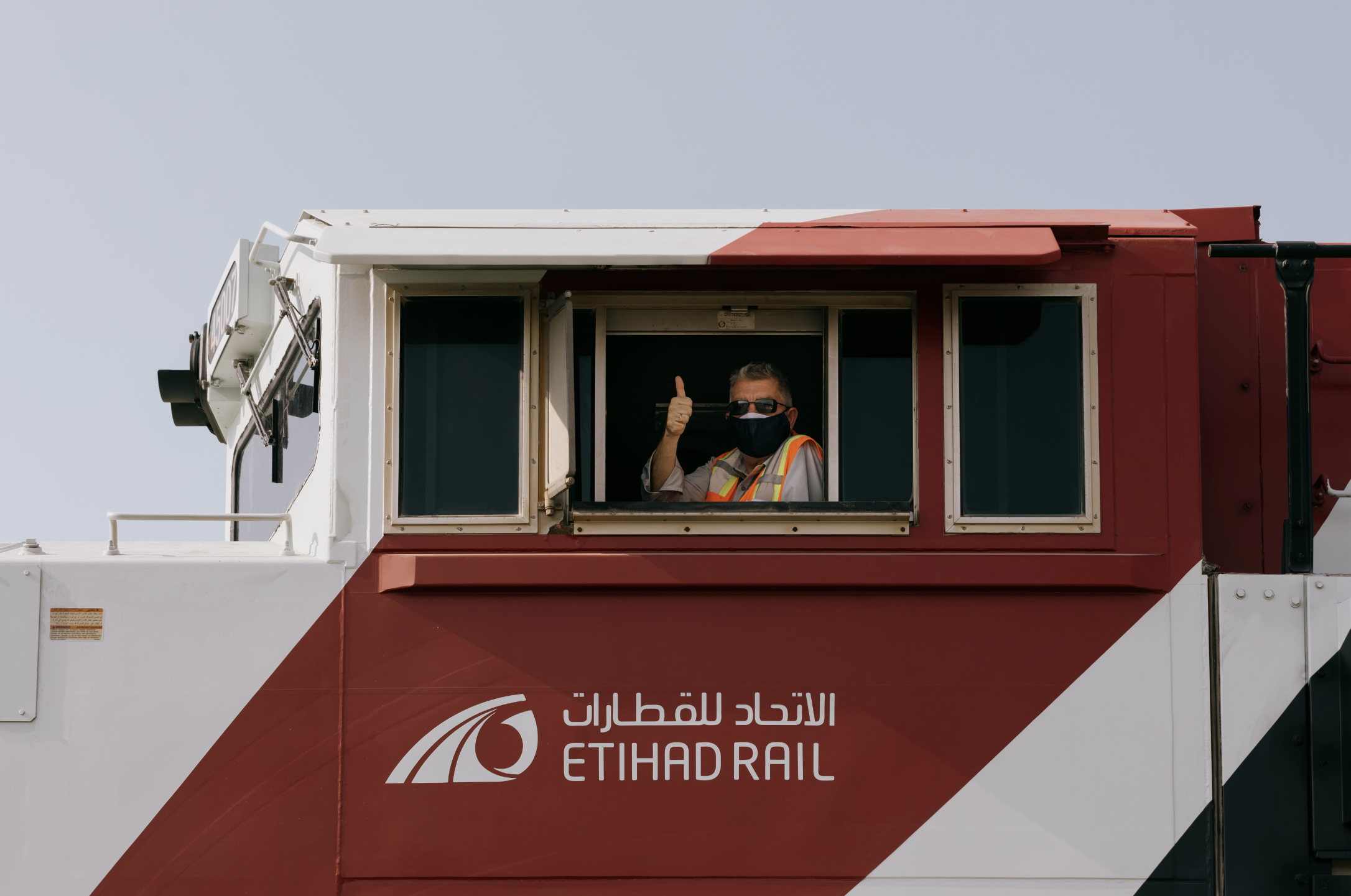 Etihad rail, worker giving the thumbs up while driving the train