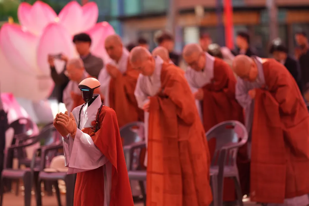 Humanoid robot in Buddhist robes greeting temple visitors – Gabi, an AI-powered robot monk, bows respectfully to visitors at Jogyesa Temple in Seoul as part of a project exploring spirituality and artificial intelligence.