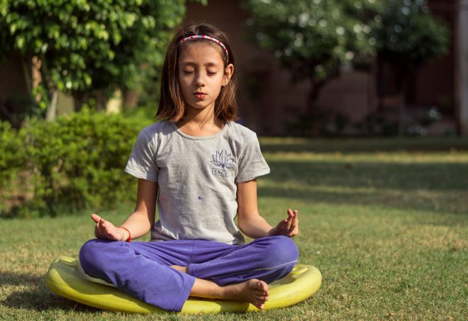 girl in lotus position yoga saying om