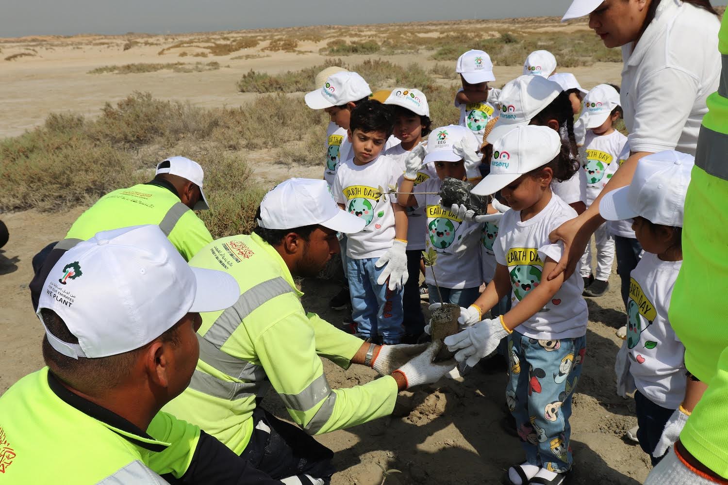 Volunteers planting mangrove trees on Earth Day 2025 at Mangrove Beach, Umm Al Quwain
