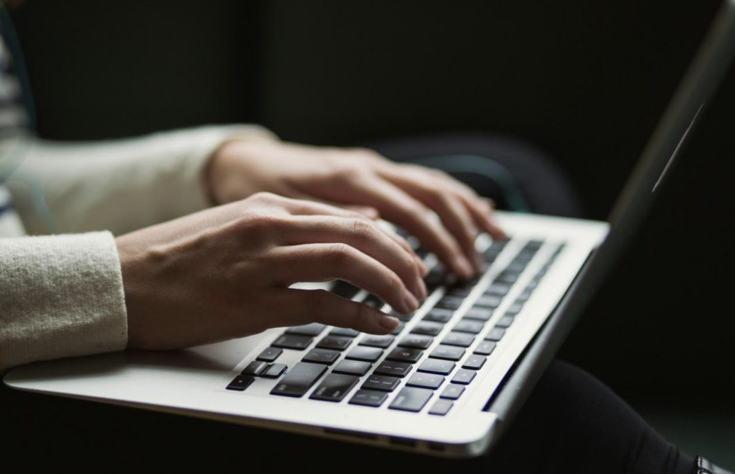 person in a white sweater using a laptop