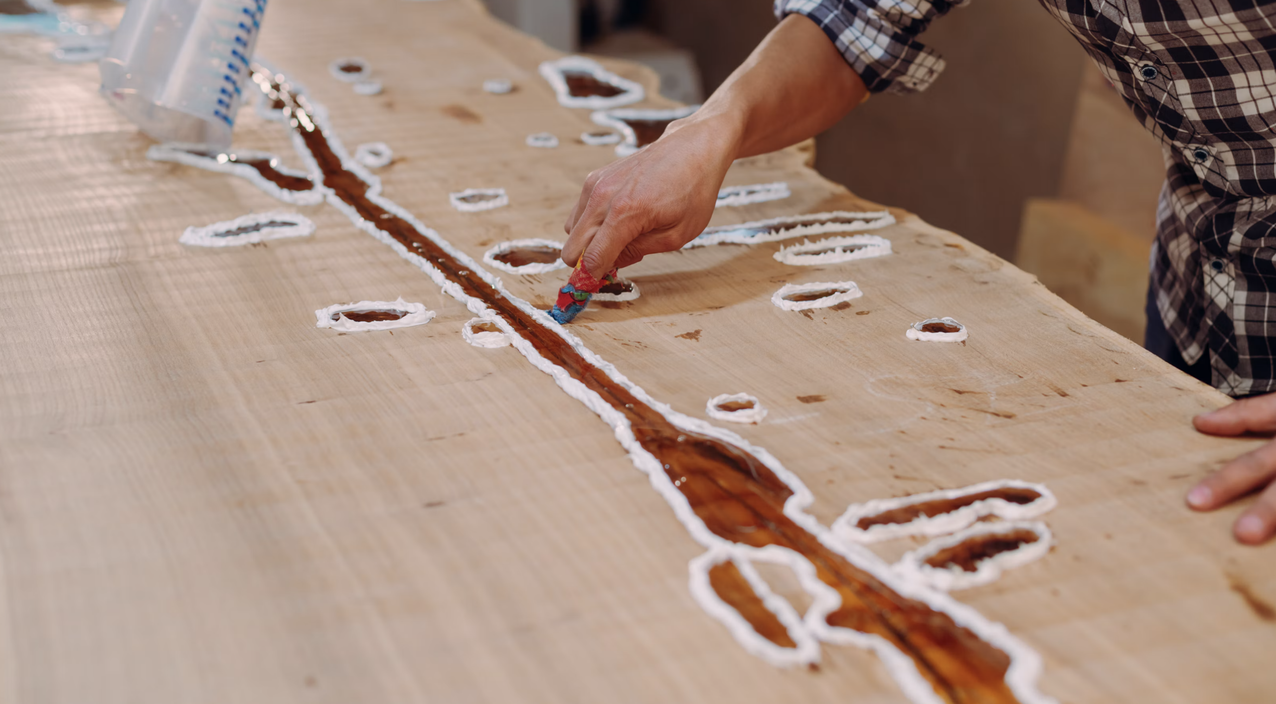 A resin table combines wood with poured epoxy resin, creating a glossy, glass-like surface from a synthetic plastic polymer.