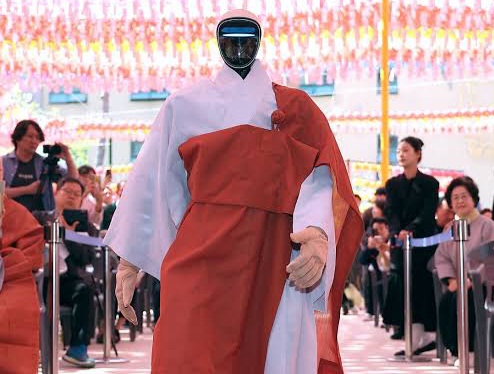 Humanoid robot in Buddhist robes greeting temple visitors – Gabi, an AI-powered robot monk, bows respectfully to visitors at Jogyesa Temple in Seoul as part of a project exploring spirituality and artificial intelligence.