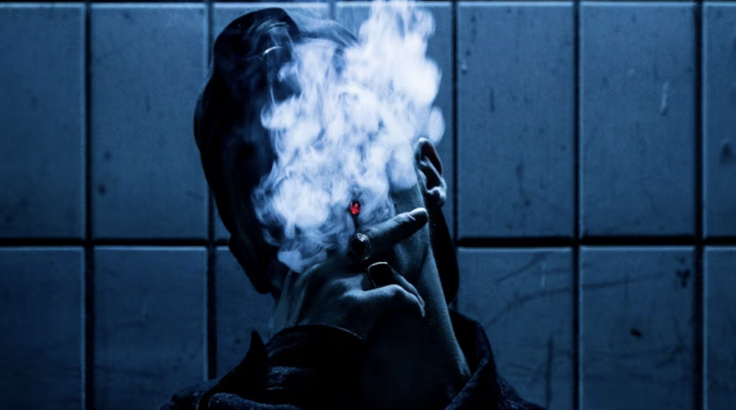Man smoking a cigarette with dense smoke surrounding his face, illustrating the risks of tobacco use.