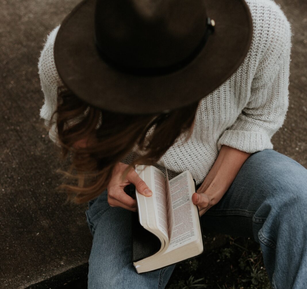 woman praying with bible, hipster hat
