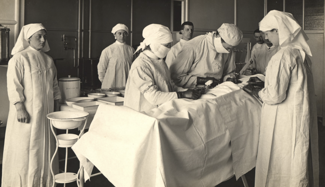 King George Military Hospital, 3rd floor Theatre Collection: Images from the History of Medicine (IHM) Contributor(s): Zwerdling, Michael, former owner Publication: [England] : [publisher not identified], [1915] Language(s): English Format: Still image Subject(s): Hospitals, Military, Operating Rooms, Surgeons, Nurses, King George Military Hospital Genre(s): Postcards Abstract: Black and white photograph of the 3rd floor operating theatre at King George Military Hospital, London, England. A surgeon is performing an operation with 7 medical personnel in attendance.