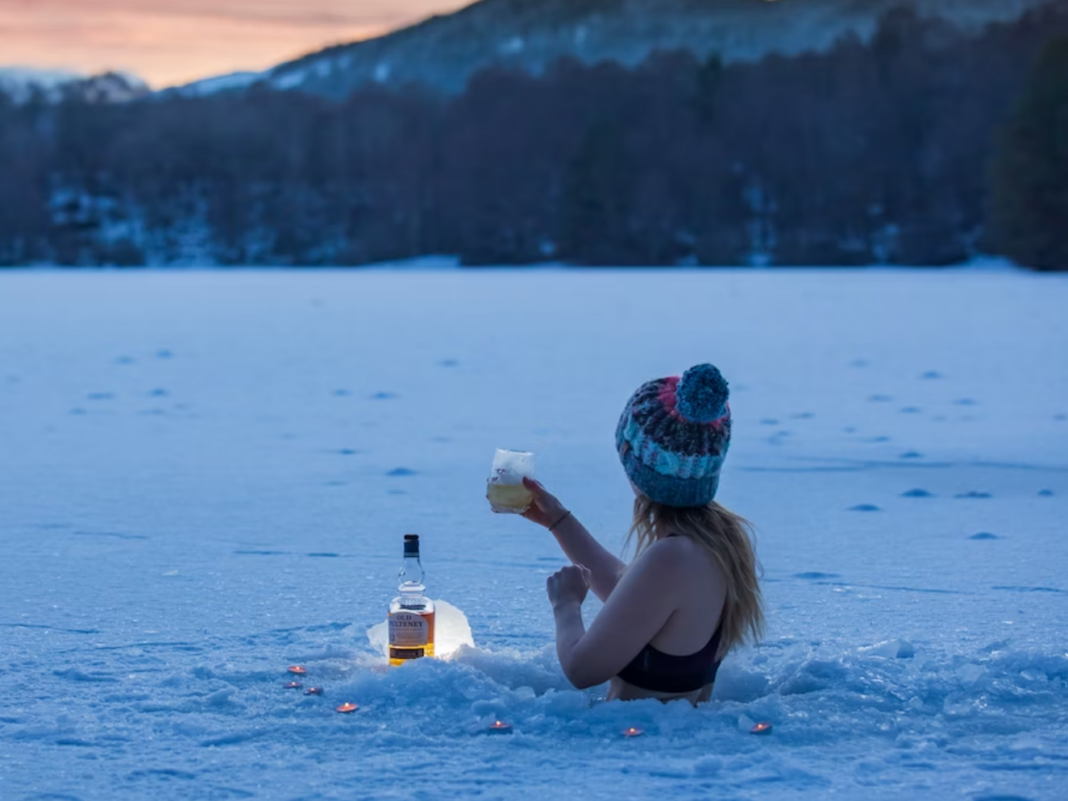 woman in ice bath in a lake drinking whiskey