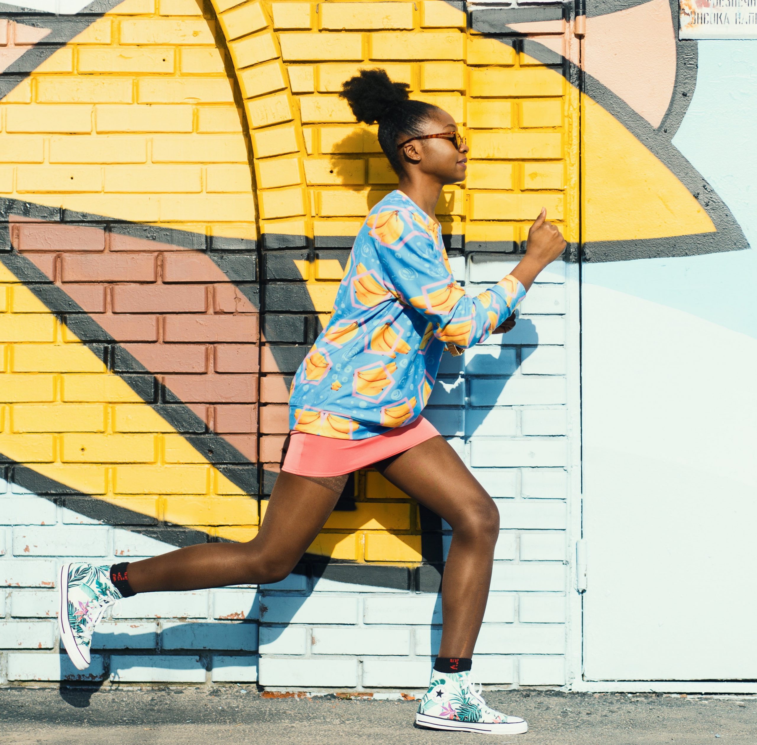 woman running behind graffiti